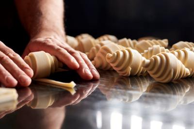 Artisan butter croissant production process, featuring hand-shaped laminated dough prepared on a worktable in a specialty bakery.