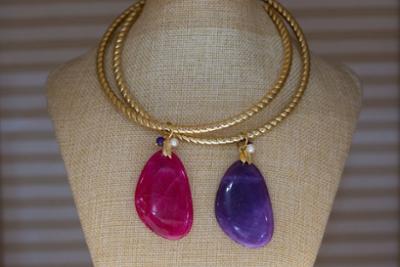 Mannequin with a necklace with two stones, one pink and one purple.