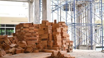 Ladrillos apilados y andamios metálicos en el interior de un edificio en construcción.