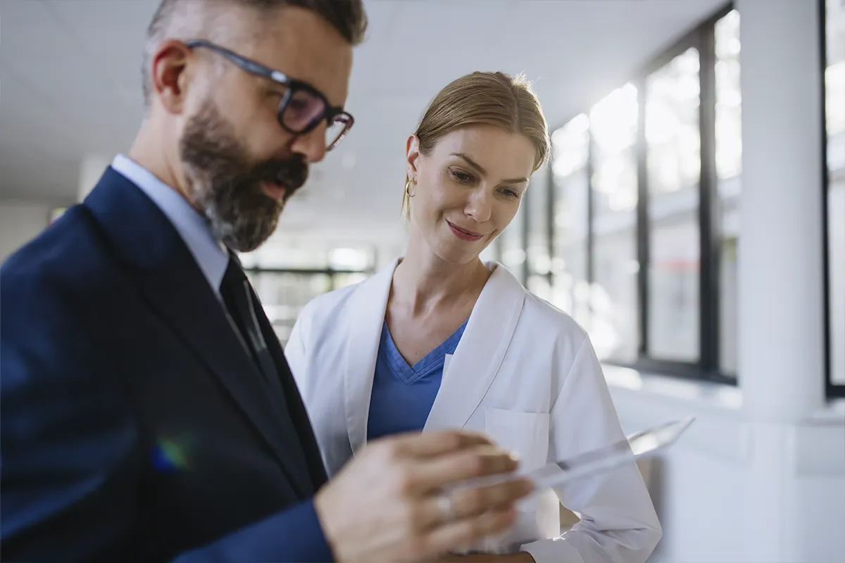 Hombre de barba mirando en una tablet un informe con doctora