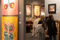 Sala de exposición con cuadros, esculturas y vitrina con vajilla.