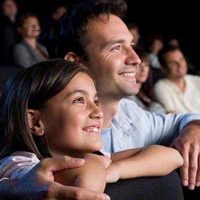 Father and daughter watching a film at the cinema