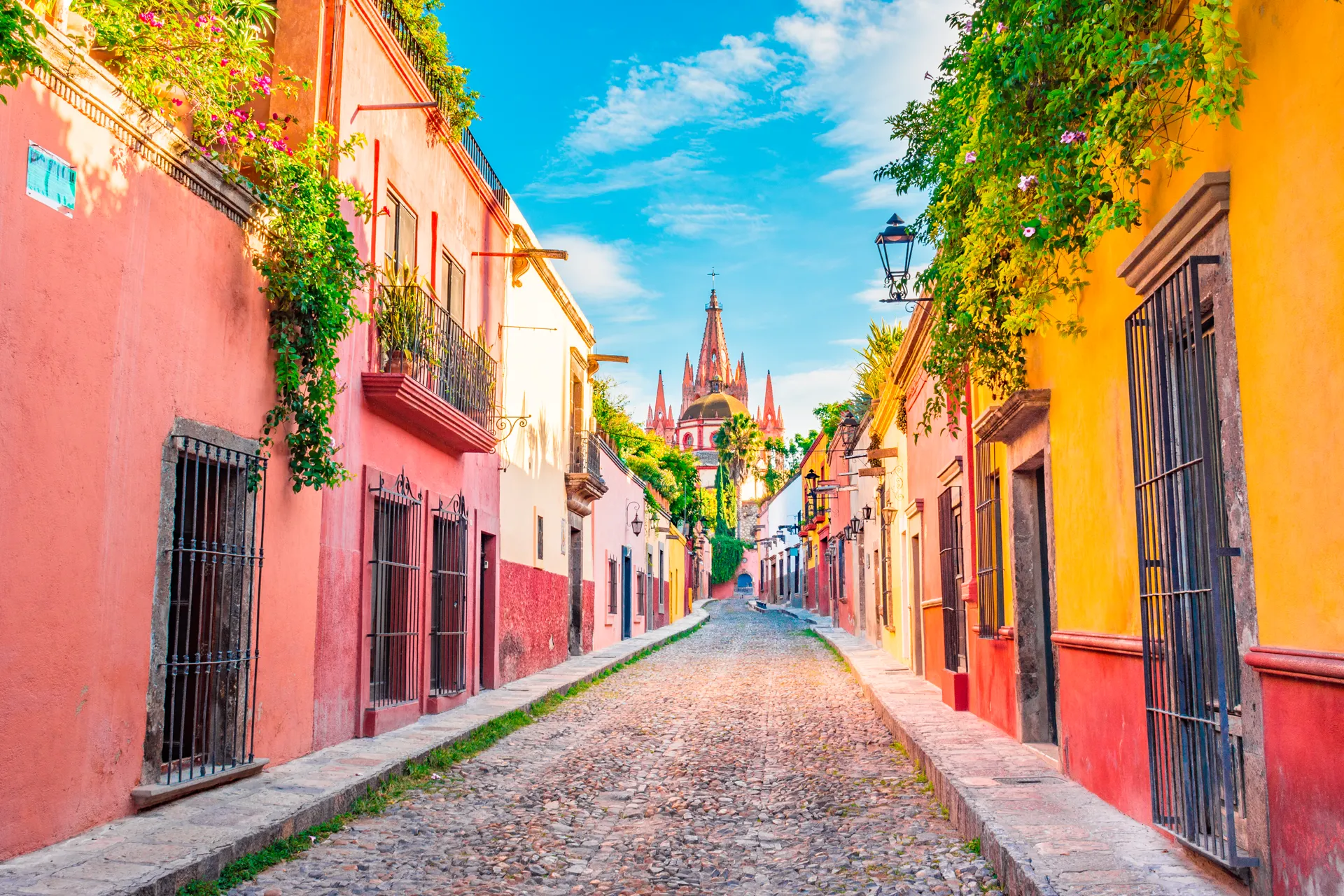 Calle con ediciones de colores vivos, un edificio en el centro y el cielo azul  Socio FITUR