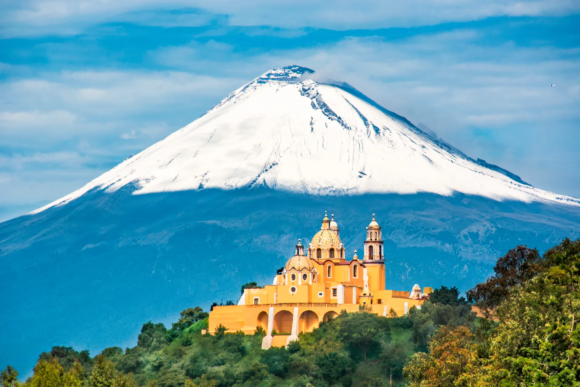 Iglesia en la montaña con vocan nevado al fondo Fitur 2026