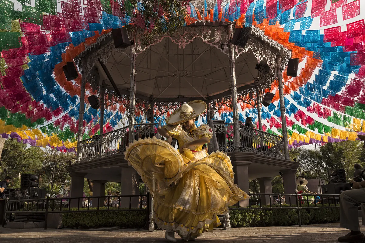 mujer bailando con traje amarillo en fiesta - Mejico en Fitur