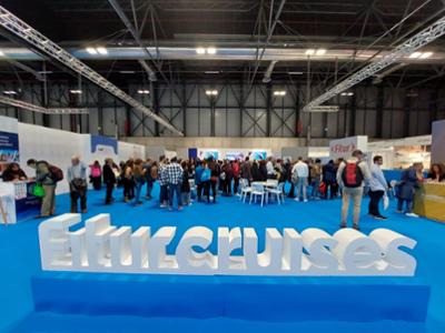 View of the FITUR Cruises section at FITUR, with numerous professionals around a large poster in this space.