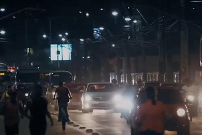 The city at night with traffic and passers-by.