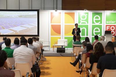 A speaker in front of the audience making his presentation in the auditorium of the GENERA trade fair.