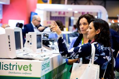 Dos mujeres conversando en frente de un stand de la feria