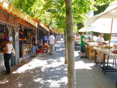 Casetas de librerías de segunda mano en la Cuesta de Moyano de Madrid, junto al Parque de El Retiro, con libros expuestos al aire libre en una tarde de primavera