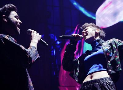 Two singers on stage holding their microphones