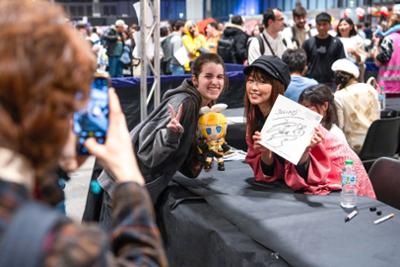 Fan posando con una invitada durante una sesión de firmas en Japan Weekend