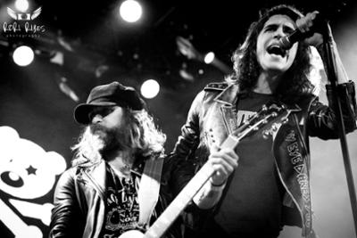 Foto de un cantante en primer plano y detrás el guitarrista en Rock en Familia