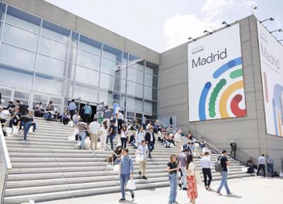 fotografia de un edificio con un cartel de google cloud summit madrid y personas sentadas en las escaleras y paseando