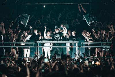 Outworld encima del escenario rodeado de gente levantando el brazo