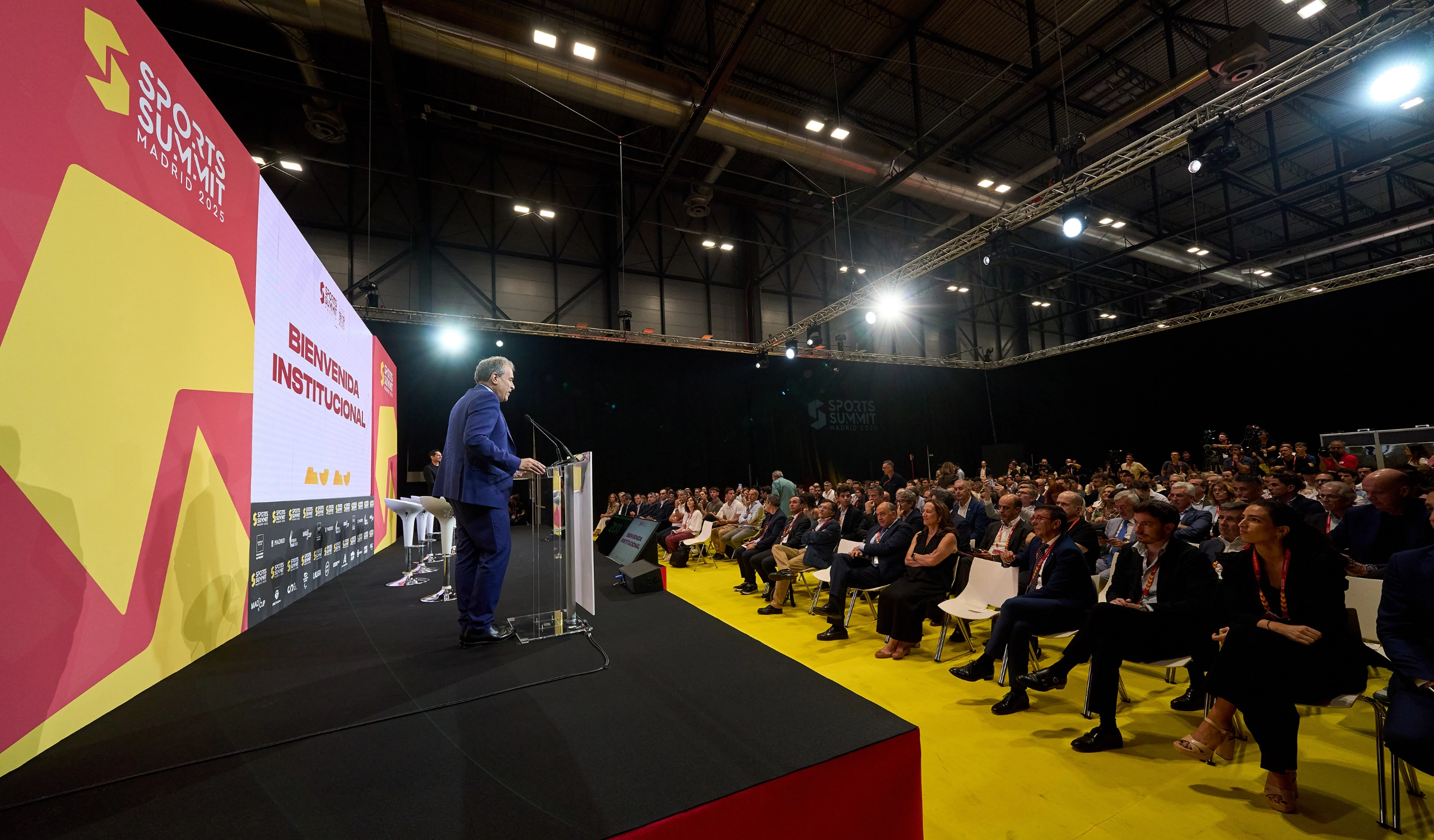 Ponentes sentados escuchando en el escenario de Sports Summit