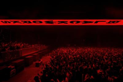 Público de blackworks-festival bailando con luces rojas encima de ellos con el nombre del evento