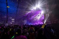 Escenario con luces y artistas cantando y el público en horteralia