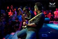 Guitarrista de rodillas tocando y detrás el cantante con un monton de personas y niños en el público en Rock en Familia