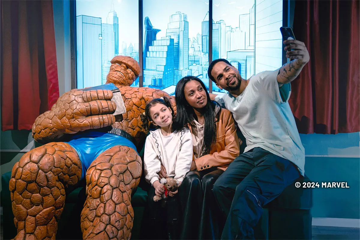 Three people having their photo taken with a Thing figure at the Marvel: Universe of Super Heroes exhibit.