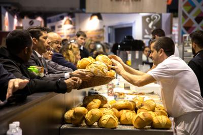 Bakery exhibitor placing loaves of bread in a basket.