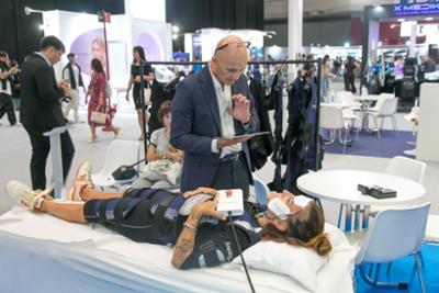 Demostración de un traje de electroestimulación muscular durante una feria profesional de tecnología y bienestar.