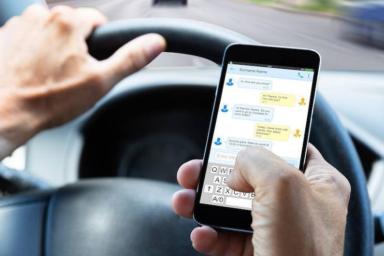 La mano de un conductor usando un móvil
