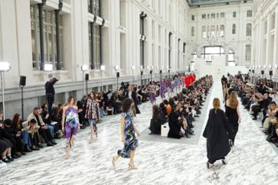 Desfile de moda en la galeria de cristal con modelos recorriendo una pasarela ante el público.