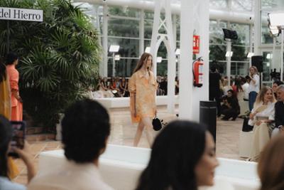 Modelo desfilando para Pedro del Hierro en un espacio interior rodeado de vegetación y asistentes durante una presentación de moda