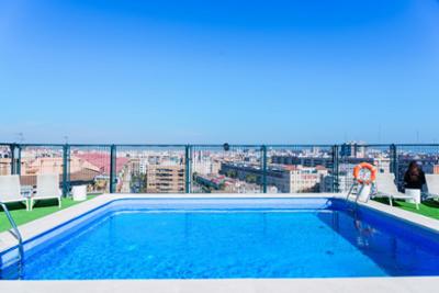 Piscina en una azotea con tumbonas y vistas panorámicas de la ciudad.
