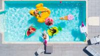 Vista aerea de una piscina con personas y colchonetas de diferentes formas y colores.