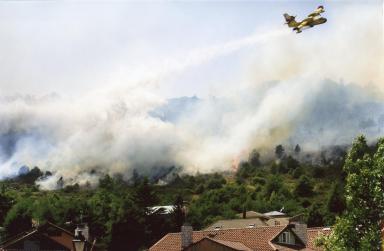 Una avioneta trabajando en la extinción de un incendio en un entorno urbano forestal