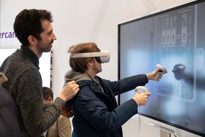 Un visitante de SIMO EDUCACION con gafas de realidad virtual interactúa con una pizarra digital