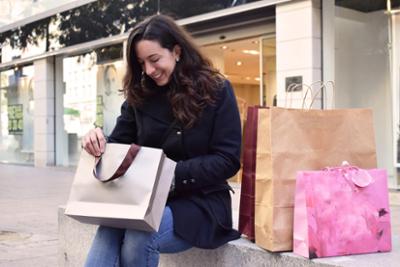 Una señora con varias bolsas de compras delante de una tienda