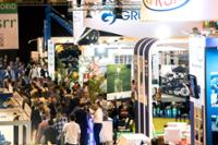 Vista general de un pasillo con varios stands y muchos visitantes.
