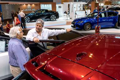 dos hombres apoyados sobre un coche rojo