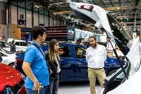 Visitantes observando un maletero de un coche.
