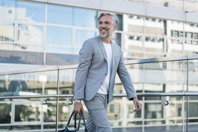 Adult man walking happily with handbag.