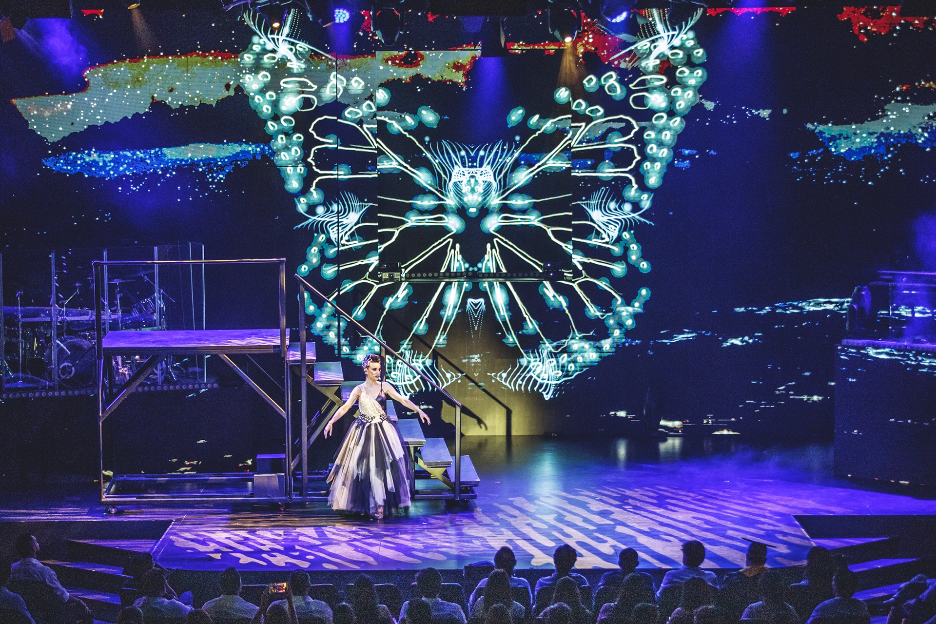 WAH singer on stage with a butterfly made of LEDs in the background